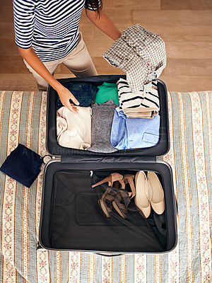 Buy stock photo High angle shot of a woman packing a suitcase on a bed
