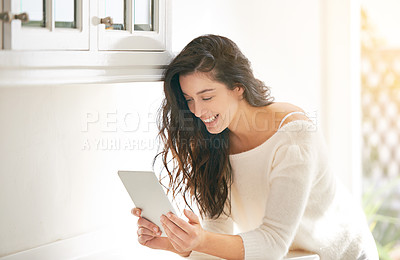 Buy stock photo Shot of a young woman using a digital tablet in her kitchen
