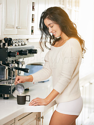 Buy stock photo Shot of a young woman making coffee in her kitchen