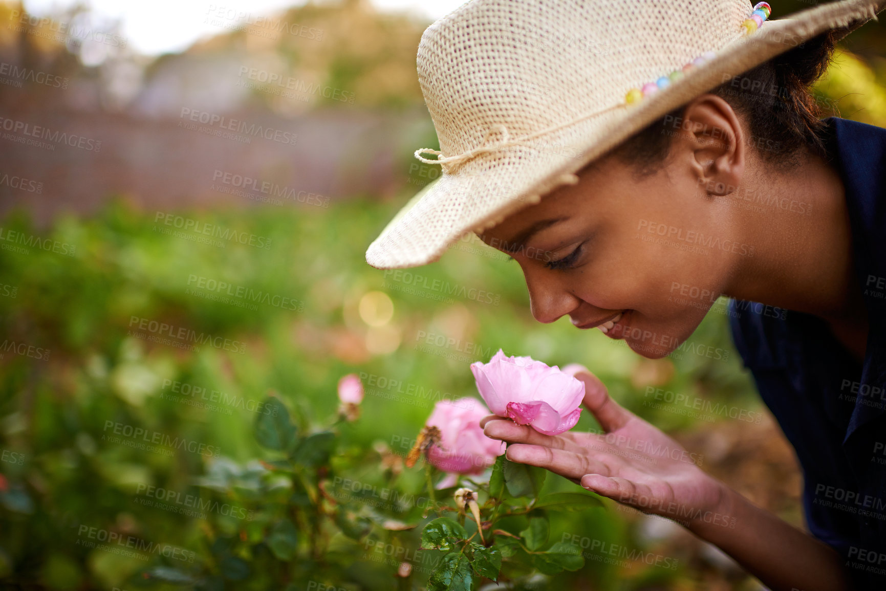 Buy stock photo Shot of a young woman admiring the roses in her garden