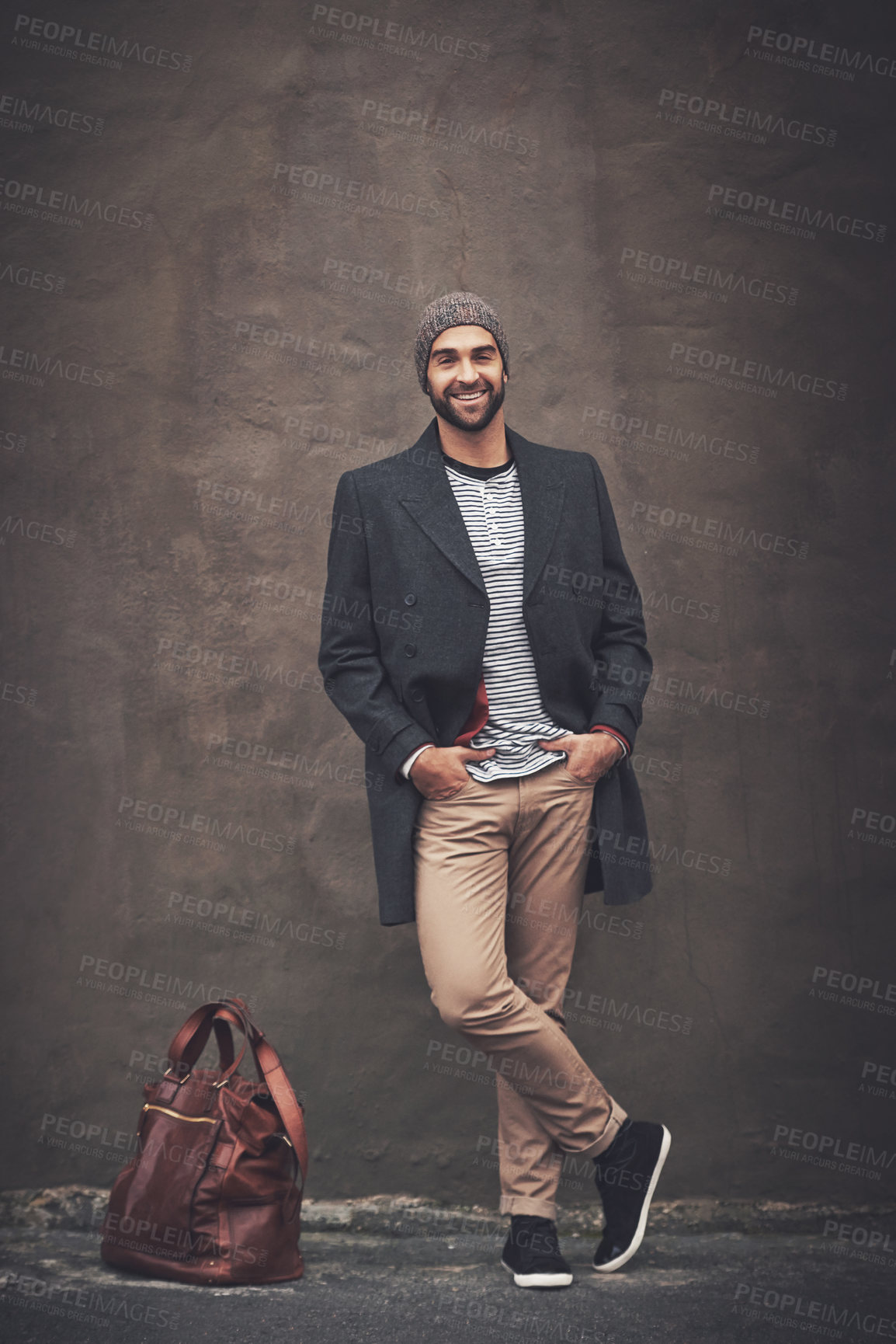 Buy stock photo Man, portrait and smile with downtown, fashion and trendy gentleman jacket. Model, winter and beanie for city, happiness or outdoor positivity for cool hipster style isolated on brown wall background
