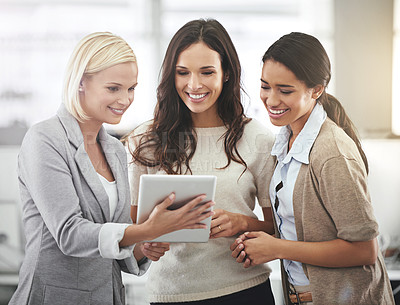 Buy stock photo Cropped shot of three businesswoman looking at a tablet in the office