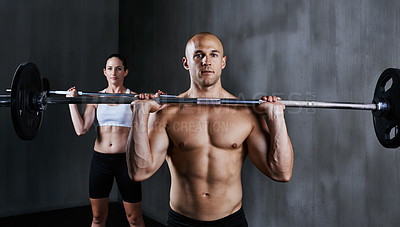 Buy stock photo Shot of two people lifting barbells during a gym workout