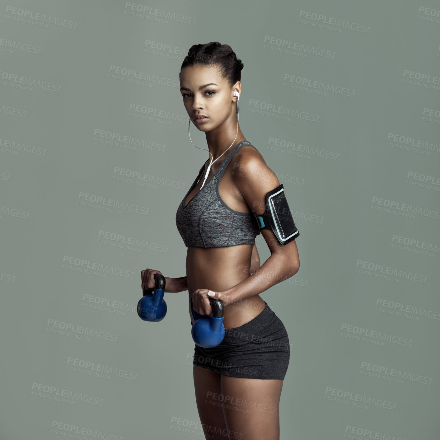 Buy stock photo Studio portrait, woman and kettlebell for workout with earphones, streaming kpop music and arm exercise. Weights, listening to sound and athlete girl by gray background for sports training and audio