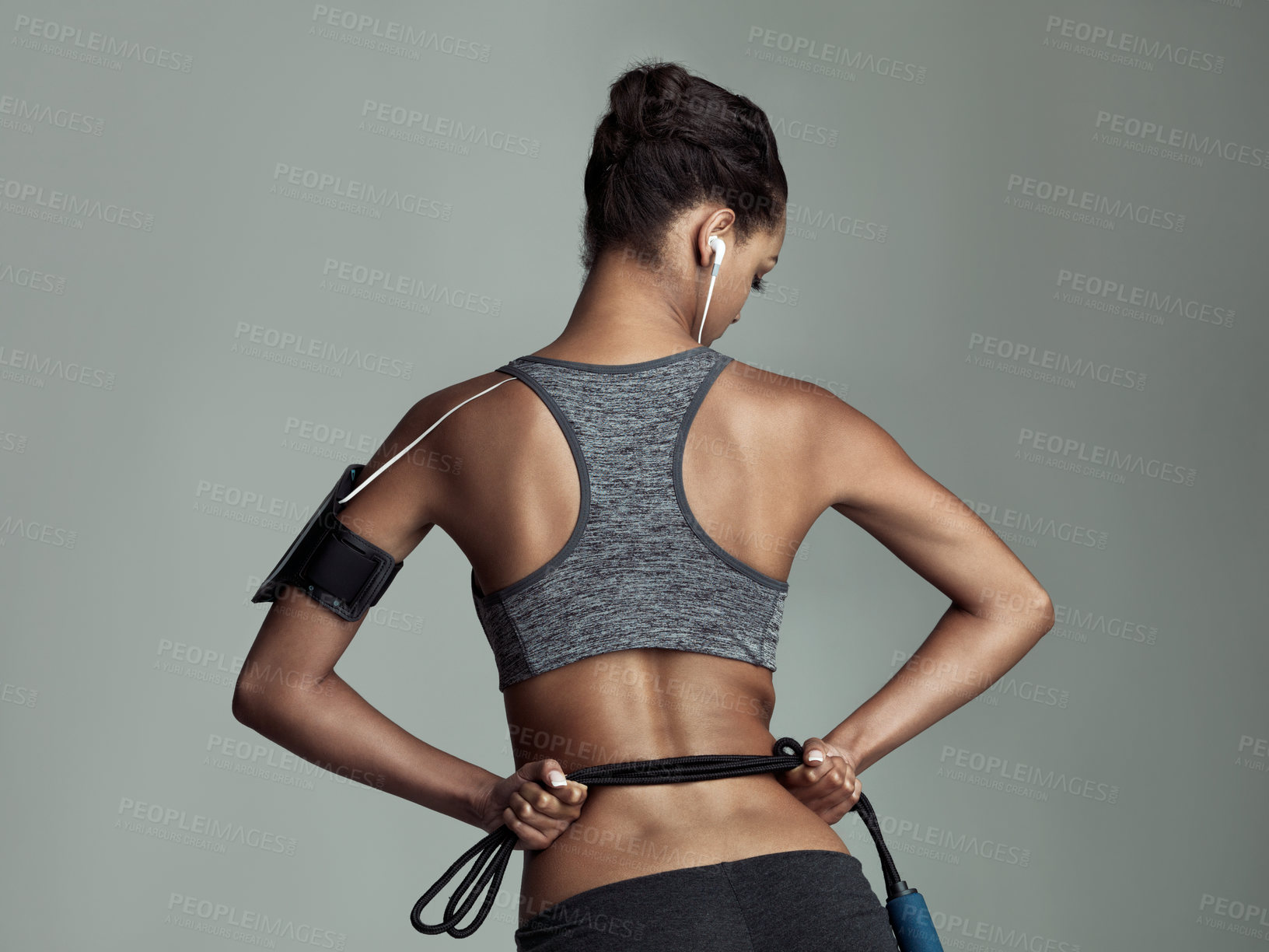 Buy stock photo Rearview studio shot of a young woman holding a rope against a gray background