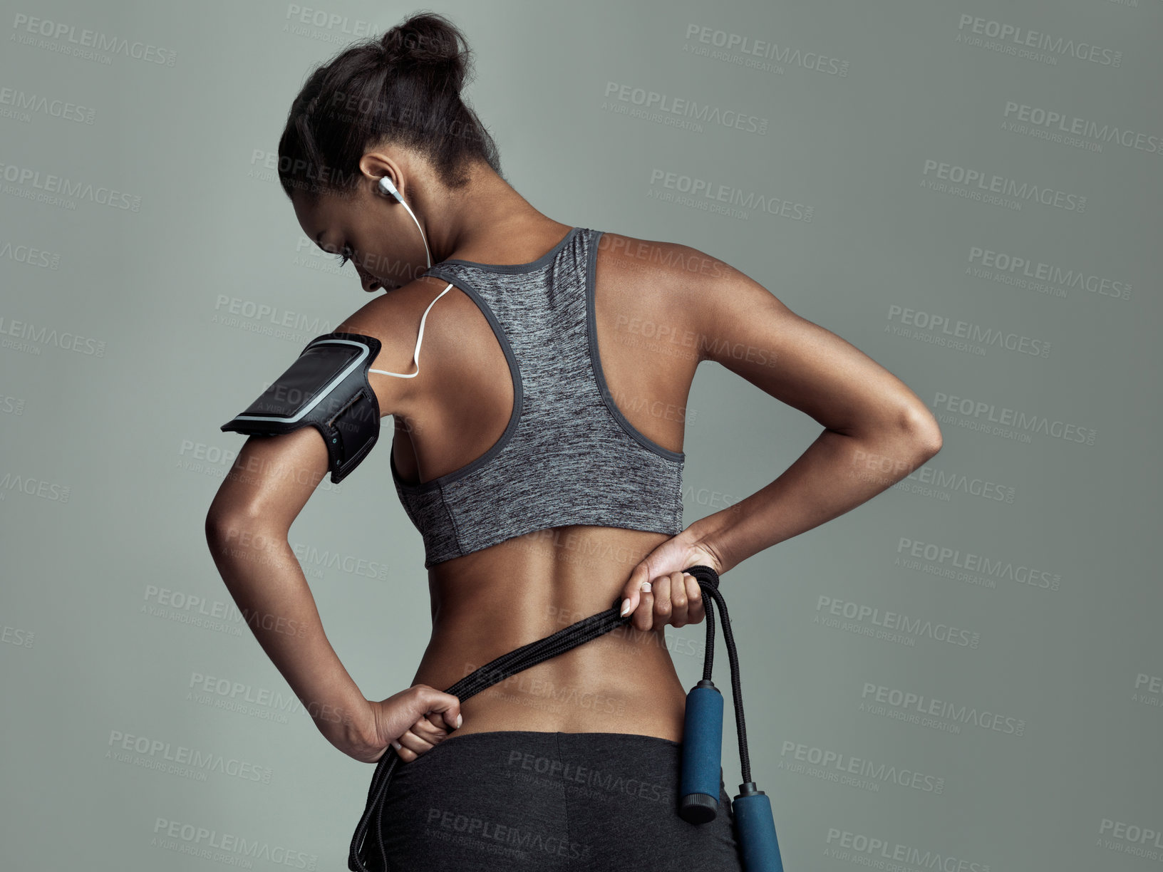 Buy stock photo Rearview studio shot of a young woman holding a rope against a gray background