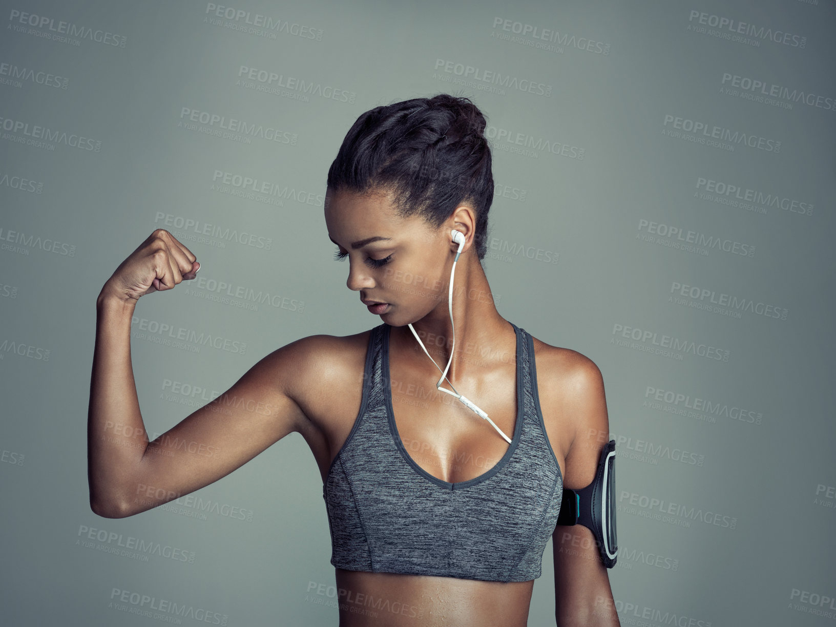 Buy stock photo Pride, woman and bicep flex in studio for exercise with technology, music and streaming. Cellphone, muscles and workout with athlete on dark background for online and podcast with fitness timer
