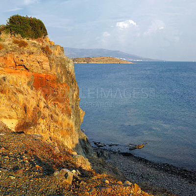 Buy stock photo Landscape, beach and outdoor with cliff, rock and waves in nature, tourism and location with mountains on horizon. Ocean, view or water by shoreline with clouds, sky and seascape in Bodrum, Turkey