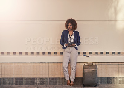 Buy stock photo A businesswoman using a digital tablet while standing with her luggage