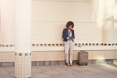 Buy stock photo A businesswoman using a digital tablet while standing with her luggage