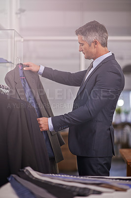 Buy stock photo Shot of a mature businessman looking at a suit in a clothing store