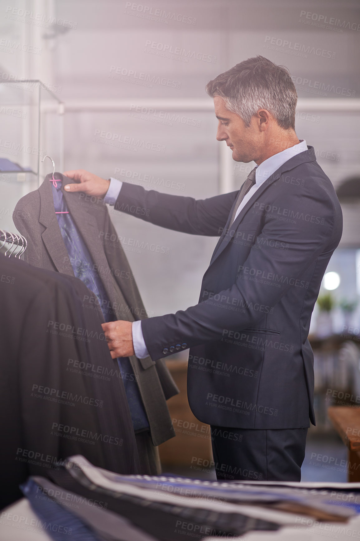 Buy stock photo Shot of a mature businessman looking at a suit in a clothing store