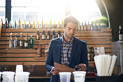 Buy stock photo Cropped shot of a male bar owner checking his supplies and stock