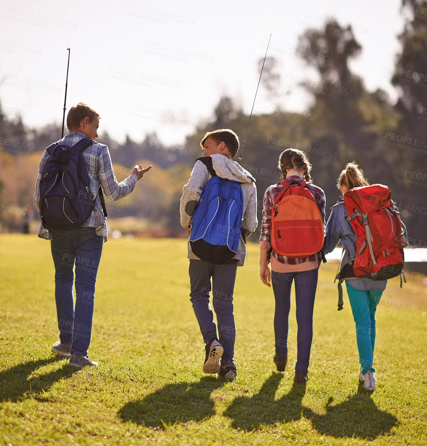 Buy stock photo Shot of a group of children wearing backpacks walking together in nature