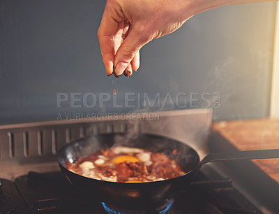 Buy stock photo Cropped shot of a person seasoning a dish on the stove