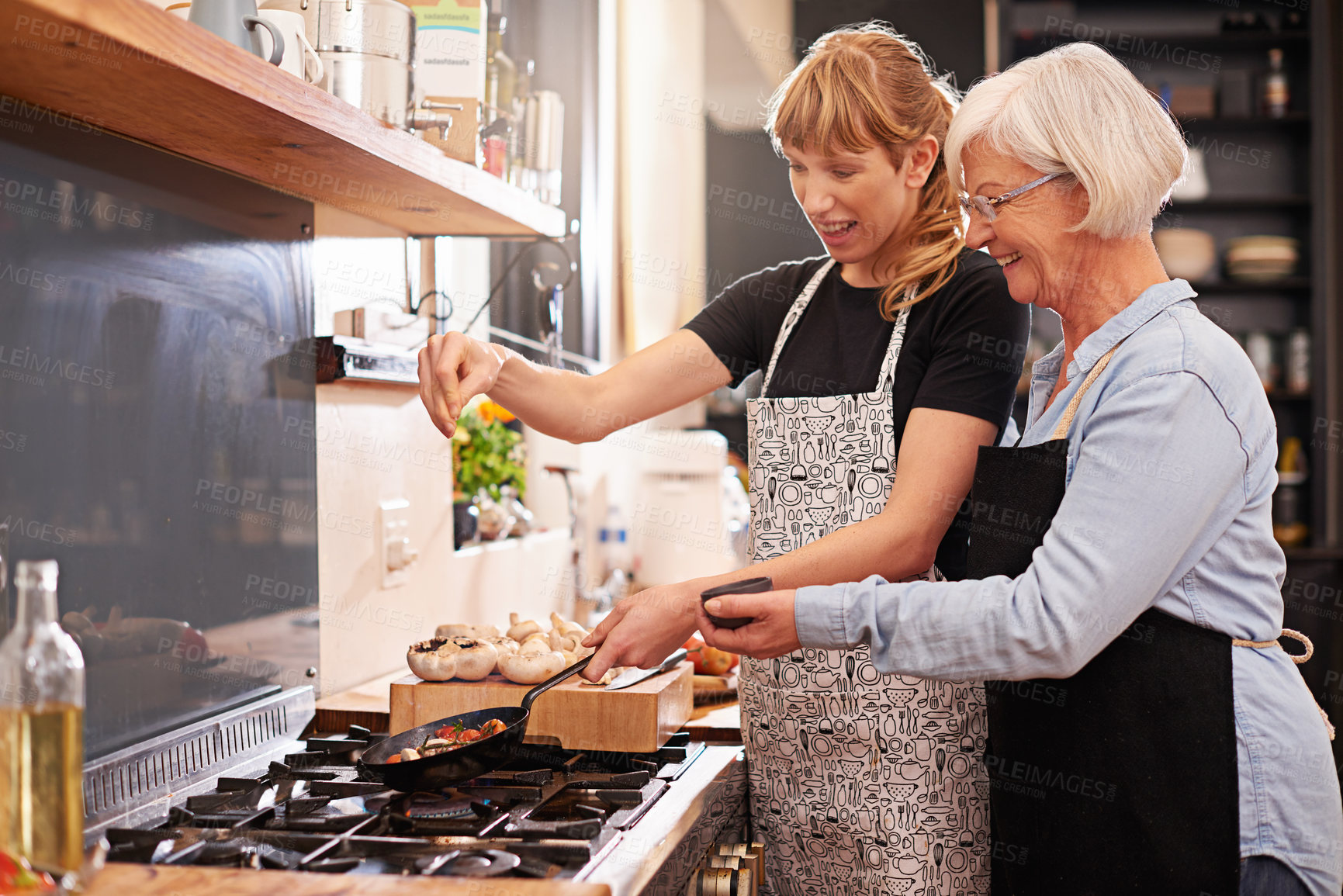 Buy stock photo Shot of a senior woman and a younger woman cooking together