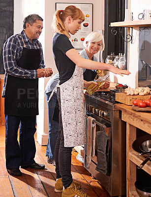 Buy stock photo Shot of two senior woman watching a young woman cooking on a stove