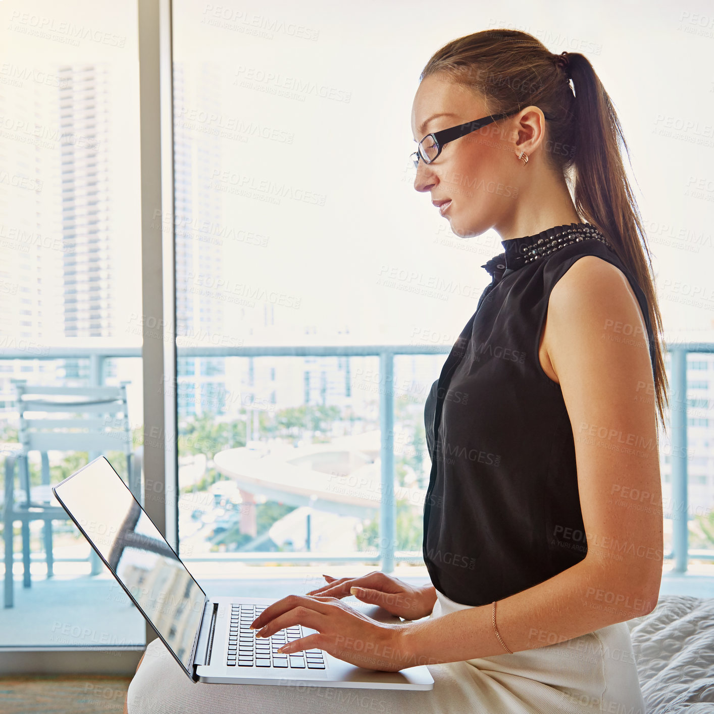 Buy stock photo A young businesswoman working on her laptop in her hotel room