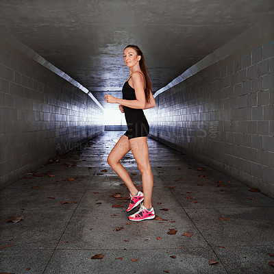 Buy stock photo Full length portrait of a sporty young woman exercising in a tunnel