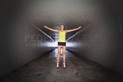 Buy stock photo Full length portrait of a sporty young woman stretching in a tunnel