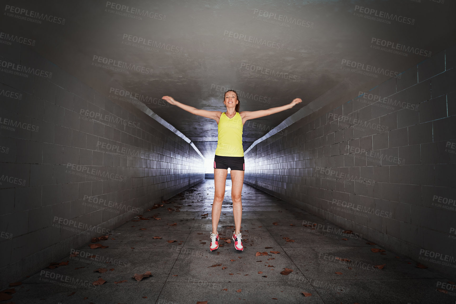 Buy stock photo Full length portrait of a sporty young woman stretching in a tunnel