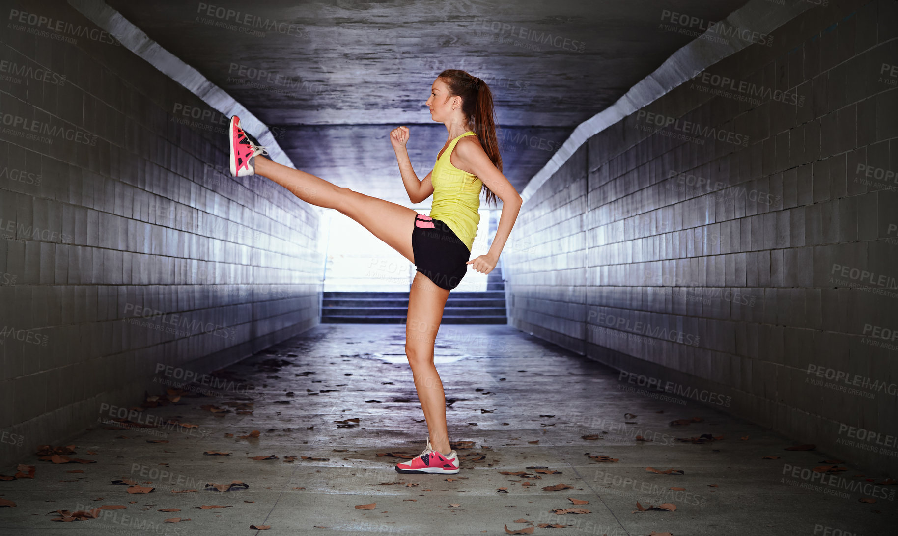 Buy stock photo Full length shot of a sporty young woman stretching in a tunnel