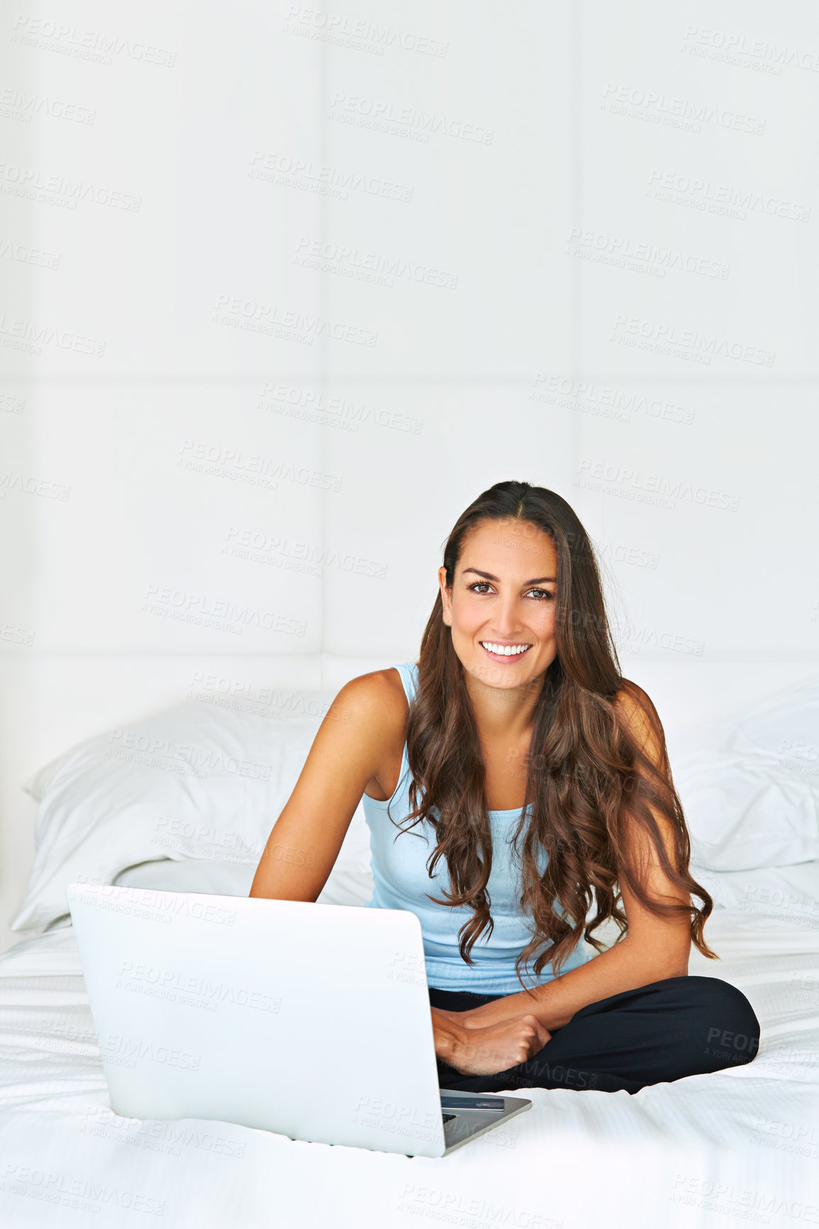 Buy stock photo Portrait of a young woman using a laptop while lying on her bed