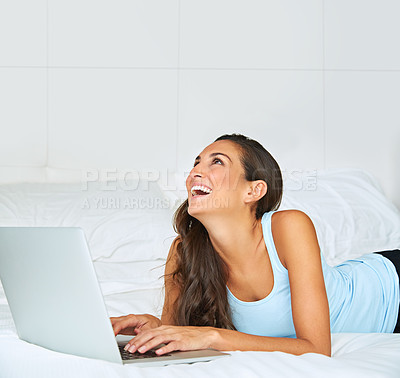 Buy stock photo Shot of a young woman using a laptop while lying on her bed