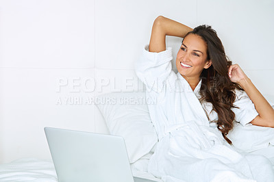 Buy stock photo Portrait of a smiling young woman using a laptop while lying on her bed