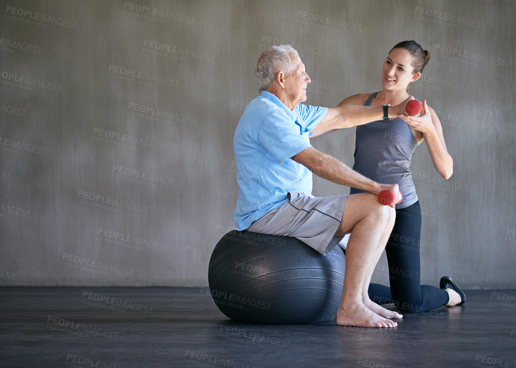 Buy stock photo Physiotherapist, dumbbells and smile of senior man on ball for fitness or rehabilitation at gym on mockup. Elderly person, weightlifting and personal trainer help for body health or physical therapy