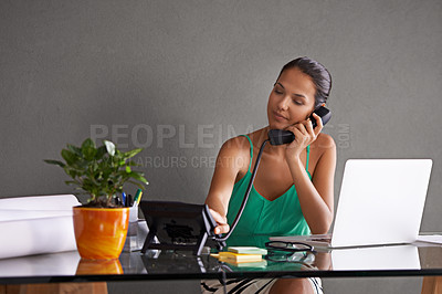 Buy stock photo Shot of a young woman talking on the phone while working from home