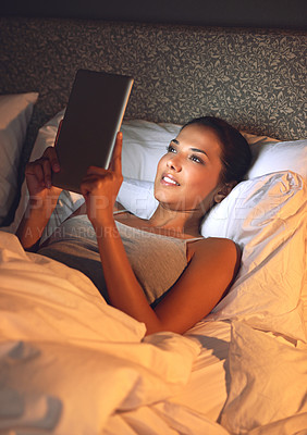 Buy stock photo Woman, night and bedroom for reading on tablet, website or social media app to relax in home, hotel or apartment. Girl, mobile touchscreen and happy with ebook, movies or video on internet in bedroom