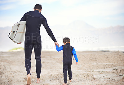 Buy stock photo Surfboard, man and child on beach, walking and holding hands on outdoor bonding adventure. Nature, father and son on ocean sand for surfing, teaching and learning together with support from back