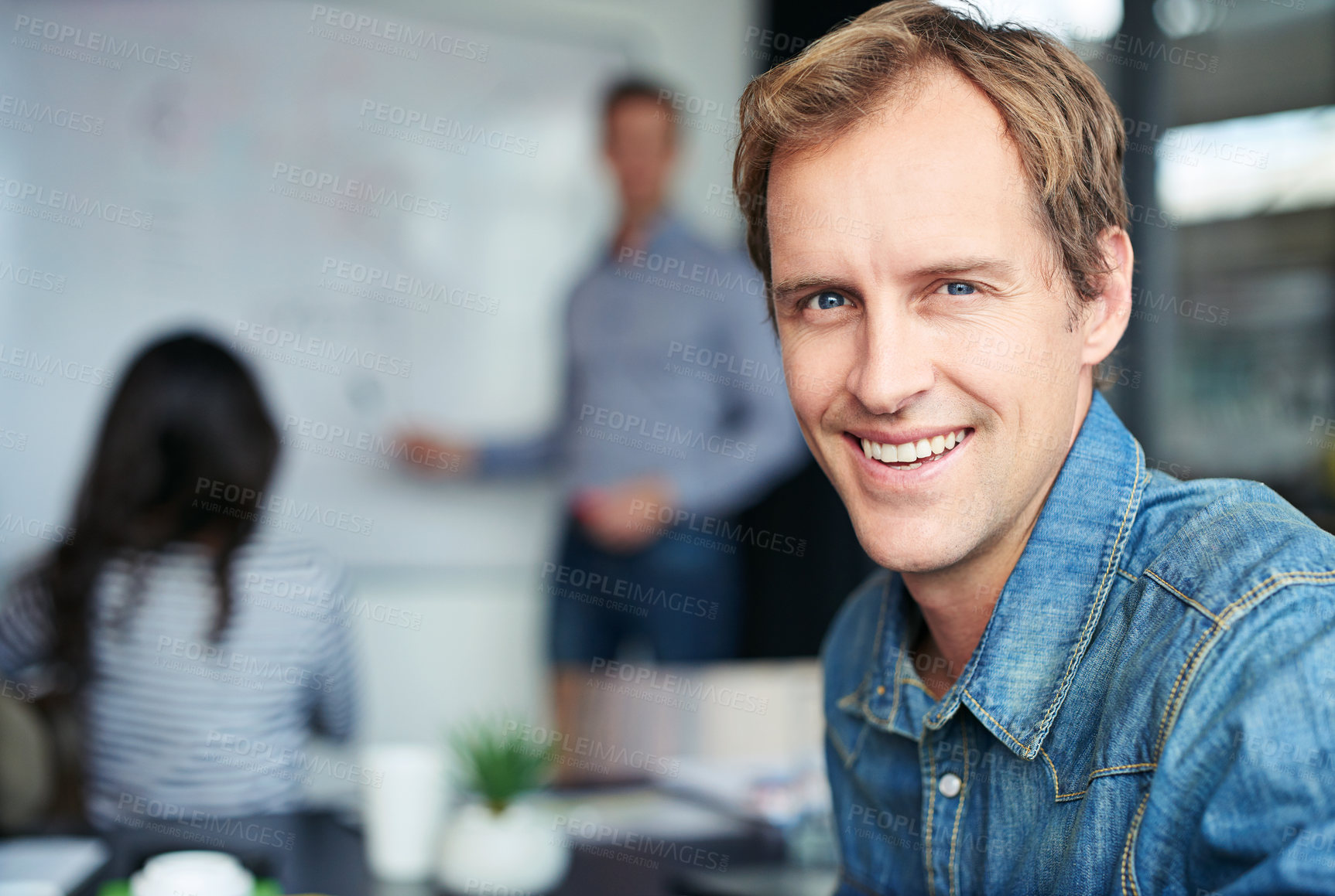 Buy stock photo Portrait of an office worker sitting in a meeting with his colleagues in the background