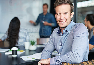 Buy stock photo Portrait of an office worker sitting in a meeting with his colleagues in the background