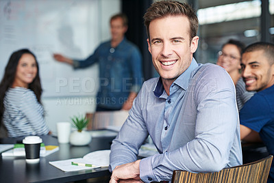Buy stock photo Portrait of an office worker sitting in a meeting with his colleagues in the background