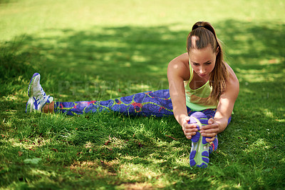Buy stock photo Shot of a young woman stretching her legs before a workout