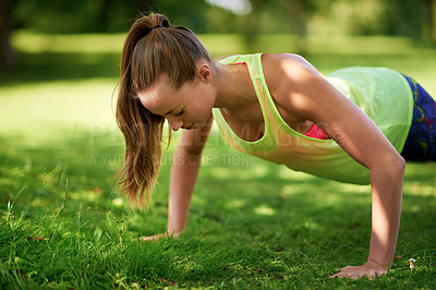 Buy stock photo Shot of a young woman doing push-ups on a grassy field