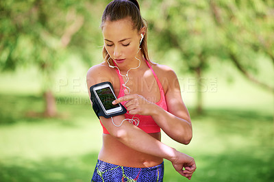 Buy stock photo Shot of a young woman arranging her playlist before her workout