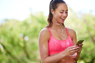 Buy stock photo Shot of a young woman using her cellphone while out for a run