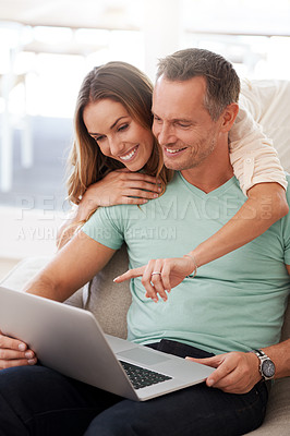 Buy stock photo Laptop, pointing and mature couple on home internet for online planning, website and to check application together. Hug, love and happy woman, partner or people on sofa, choice or reading on computer