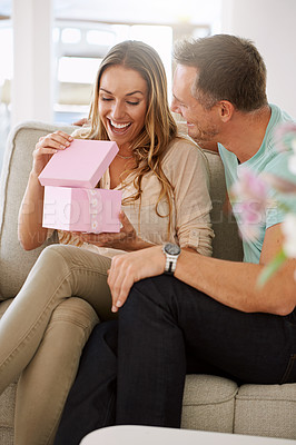 Buy stock photo Happy woman, surprise and open gift of man in lounge, excited and couple to celebrate valentines day in home. Husband, love and present for wife with kindness, gratitude and wow together on weekend