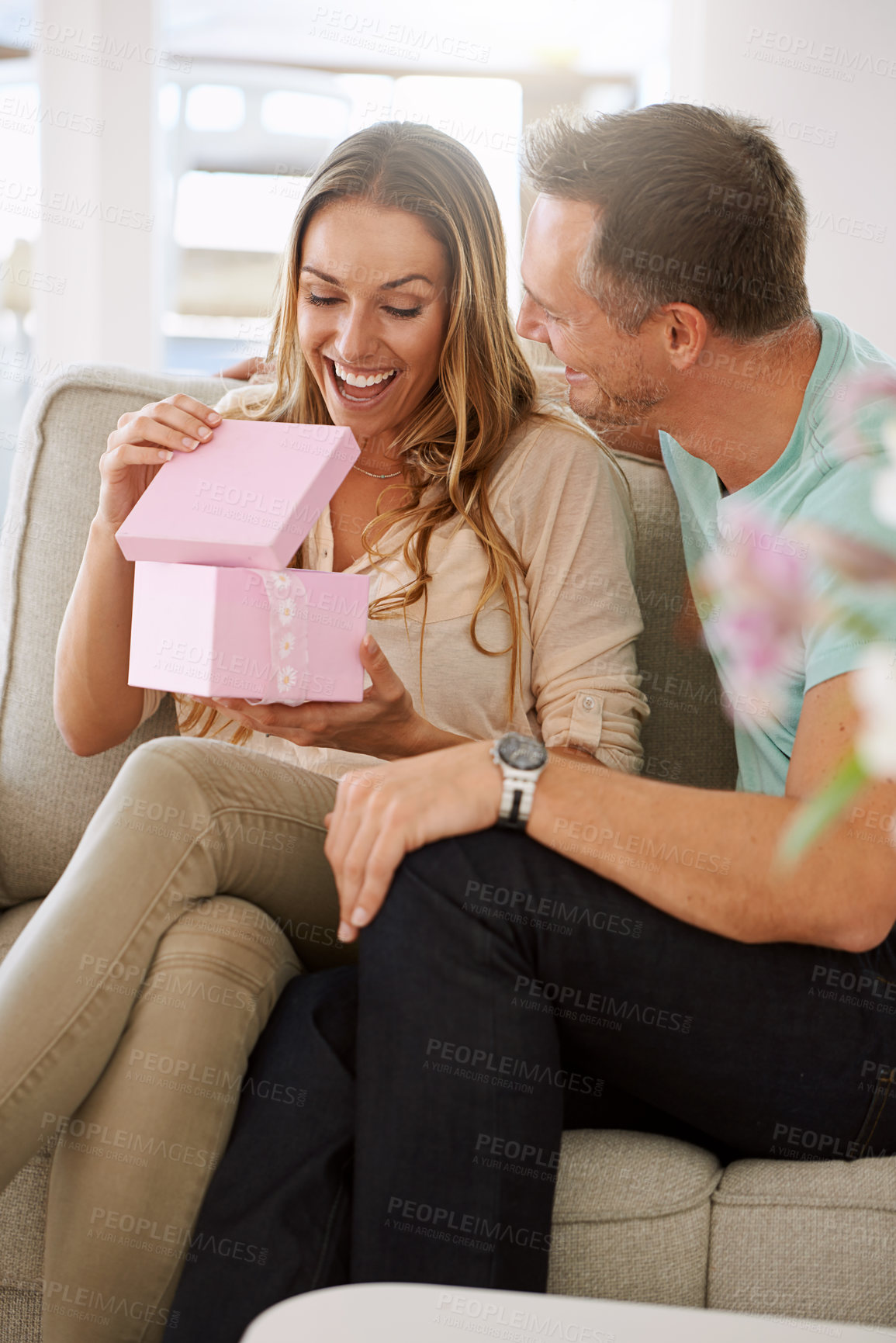 Buy stock photo Happy woman, surprise and open gift of man in lounge, excited and couple to celebrate valentines day in home. Husband, love and present for wife with kindness, gratitude and wow together on weekend