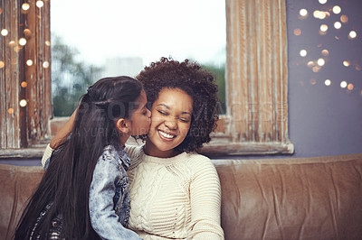 Buy stock photo Mother, child and kiss cheek on couch in home for weekend relaxing or holiday bonding, love or support. Woman, daughter and connection in apartment living room for vacation care, youth or parenting