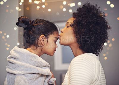 Buy stock photo Shot of a mother kissing her daughter on the forehead in the bathroom