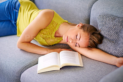 Buy stock photo Shot of a young woman sleeping beside a book on her sofa at home