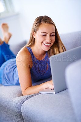 Buy stock photo Shot of a young woman using her laptop on the sofa at home