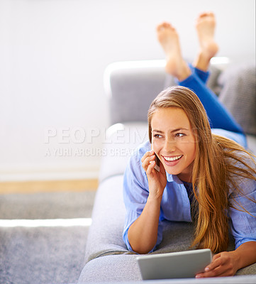Buy stock photo Shot of a young woman talking on her cellphone while holding a digital tablet