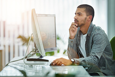 Buy stock photo Shot of a young designer working at his computer in an office