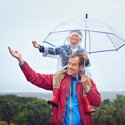 Buy stock photo Father, child or family with an umbrella in rain outdoor for fun, happiness and quality time. Happy man and boy kid in nature with hand to catch water drops for learning, freedom and travel or play